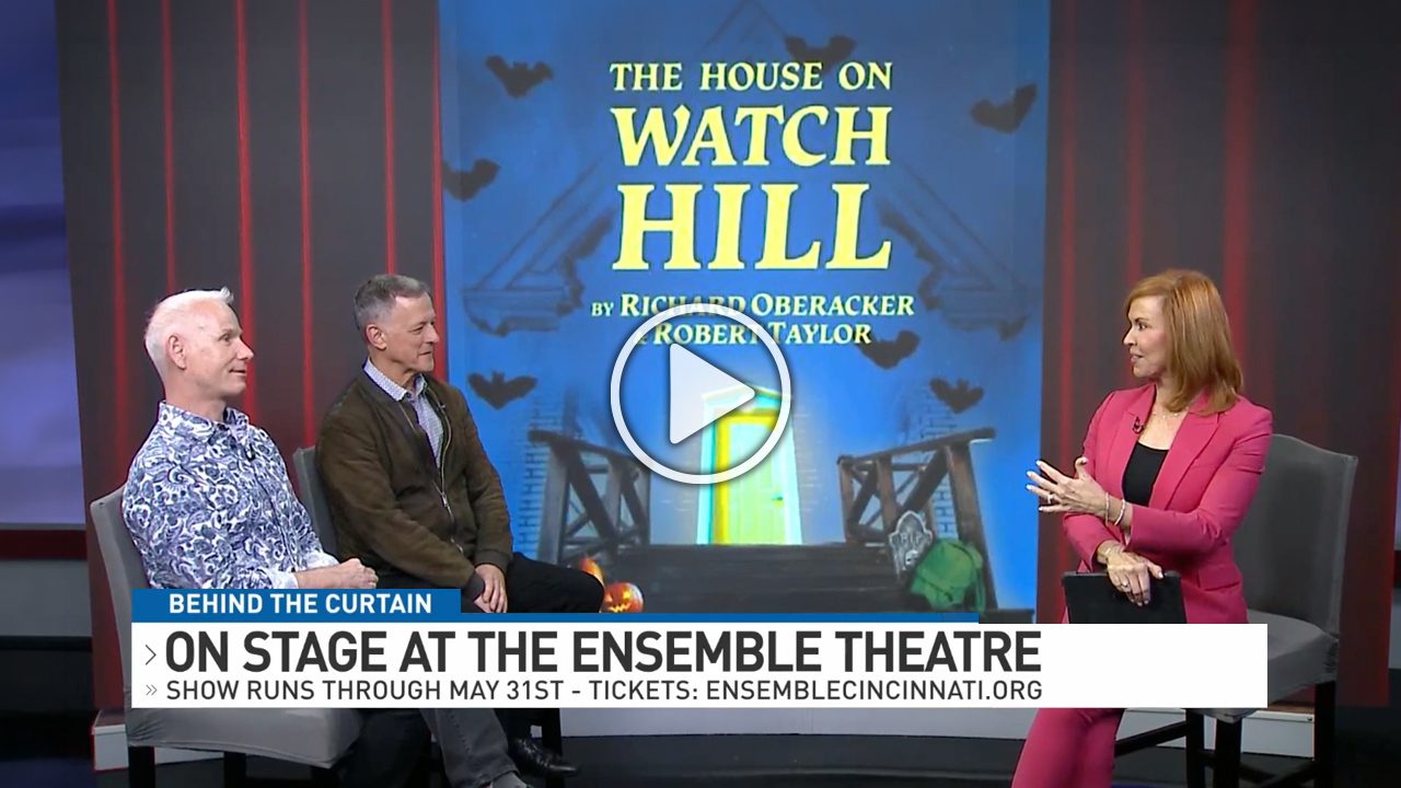 Three people sit and talk on a TV set with a backdrop displaying "The House on Watch Hill" and information about the show's run at the Ensemble Theatre.