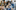 A group of students all looking at something and laughing together. They are in a classroom setting.